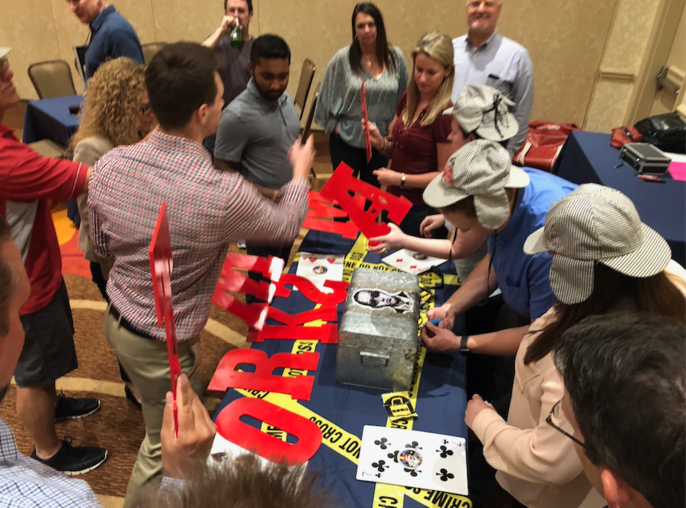 Escape-Game-Ventureupcom | Team Building Activities & Techniques Team members play the Escape the Case table team building game in a conference room.