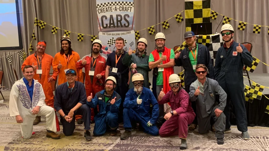 Team poses in racing gear after completing Venture Up's Create-A-Craft Cars team-building challenge.