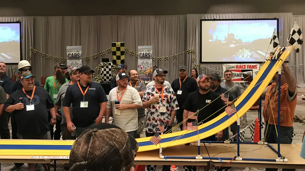 Participants watch their mini-cars race in a team building car themed event.