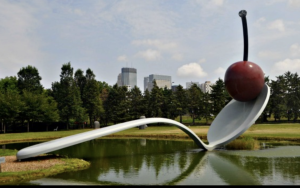 Minneapolis spoon with cherry, backdropped by cityscape and park.