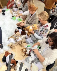People at a plush-toy stuffing station, filling and assembling stuffed animals from piles of toys and cotton fluff. | Team Building Activities & Techniques