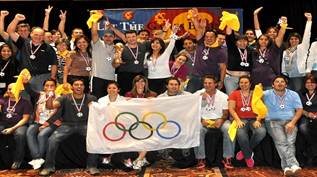 Group of people posing for a photo, holding a banner with the Olympic rings. | Team Building Activities & Techniques